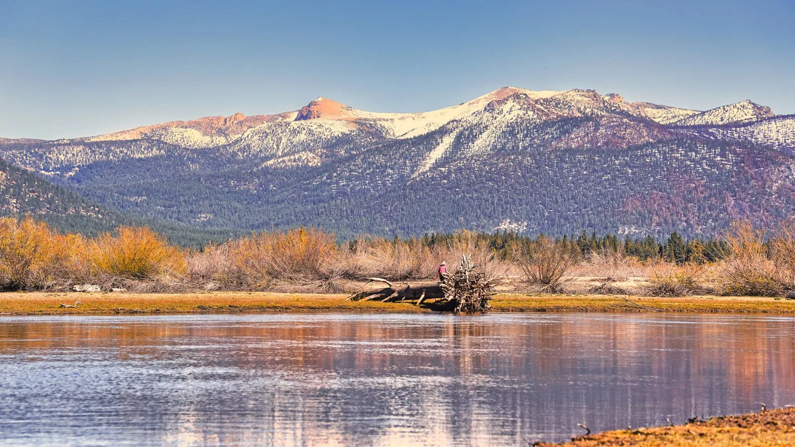 Majestic mountain scene with snow-capped peaks and a calm river in winter.
